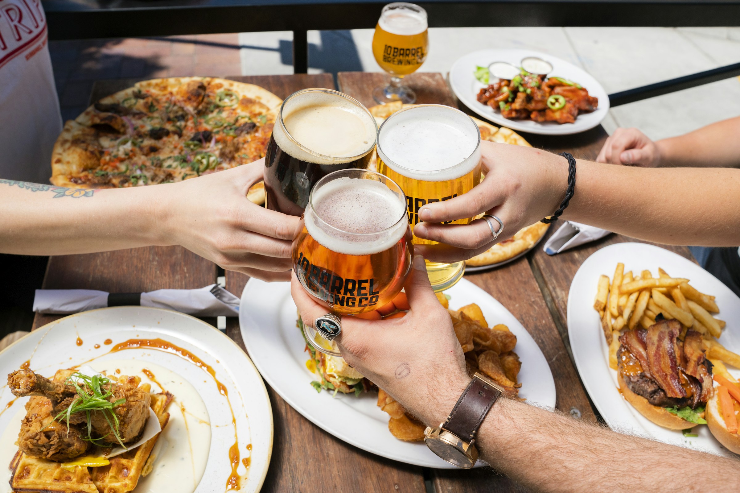 Des amis trinquent autour de pizzas et de plats